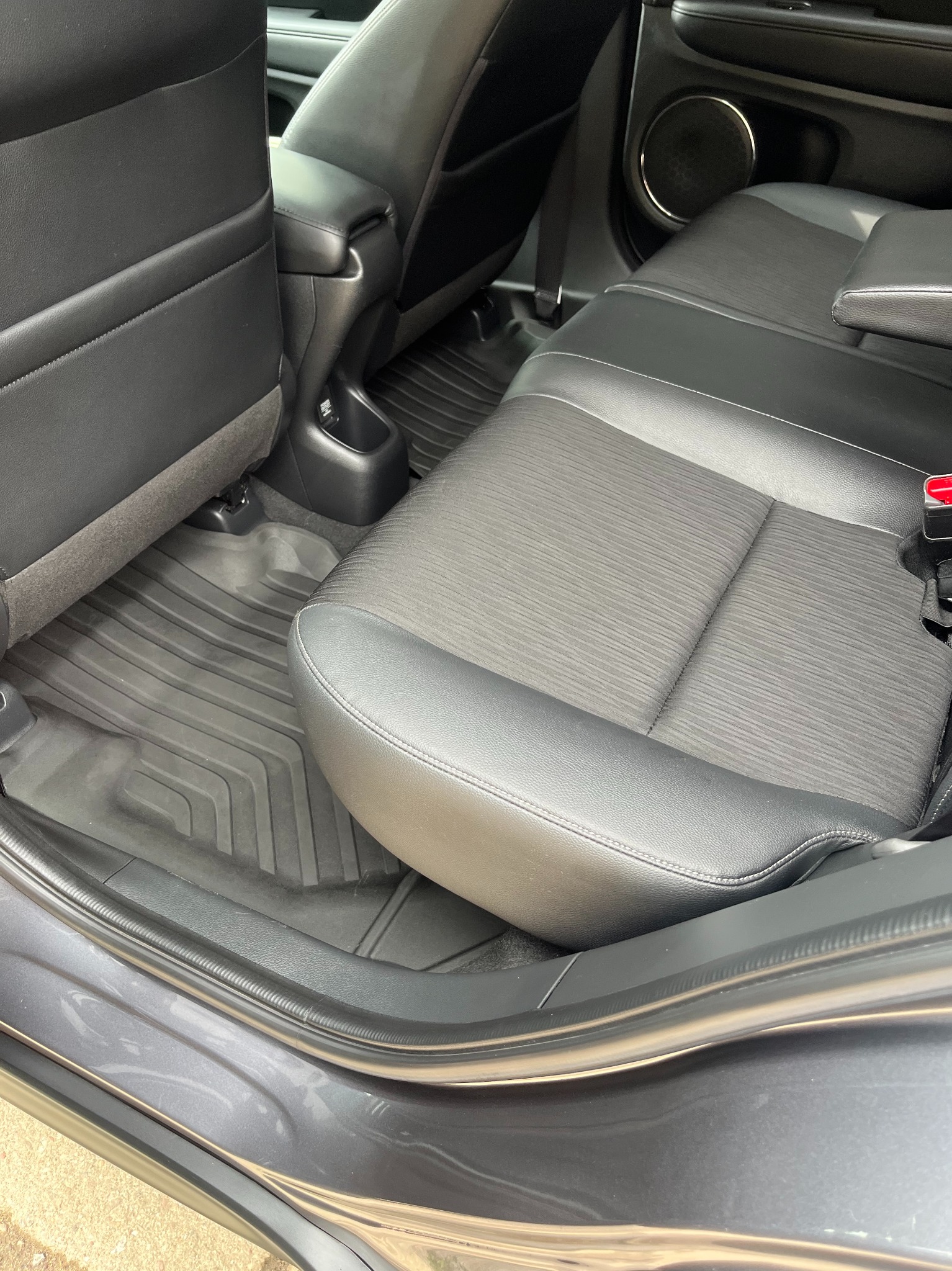 Wnętrze auta z czarną tapicerką, widoczne tylne siedzenie, podłoga z gumowymi dywanikami i fragment karoserii przy otwartych drzwiach. Czyste i zadbane.