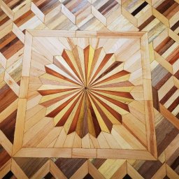 Aleksandr Lukashuk - Dekoracyjna podłoga z parkietu ułożona we wzór rozety i rombów, z wykorzystaniem różnych odcieni drewna, widok z góry.