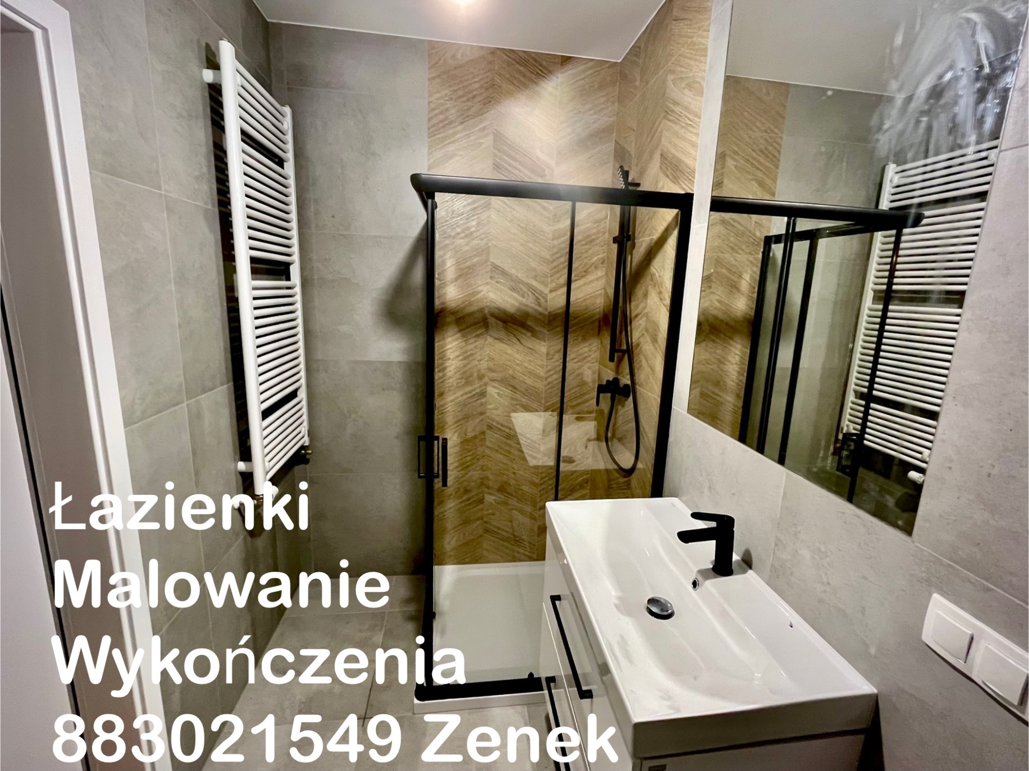 Nowoczesna łazienka z kabiną prysznicową typu walk-in, umywalką z czarną armaturą i grzejnikiem drabinkowym. Ściany wykończone płytkami w odcieniach szarości i beżu.