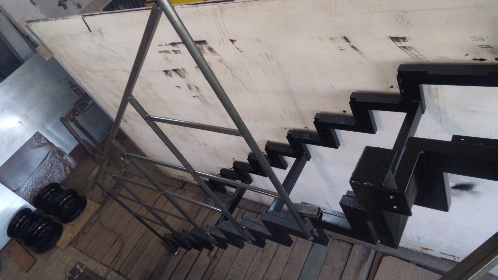 Metalowa konstrukcja schodów z elementami spawanej ramy i stopnicami w trakcie montażu, widok z góry, surowy stan wykończenia.