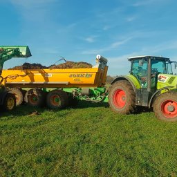 Domar - Dwa traktory na zielonym polu: jeden z ładowarką załadowuje przyczepę Joskin ziemią z korzeniami, drugi traktor Claas Axion czeka obok.