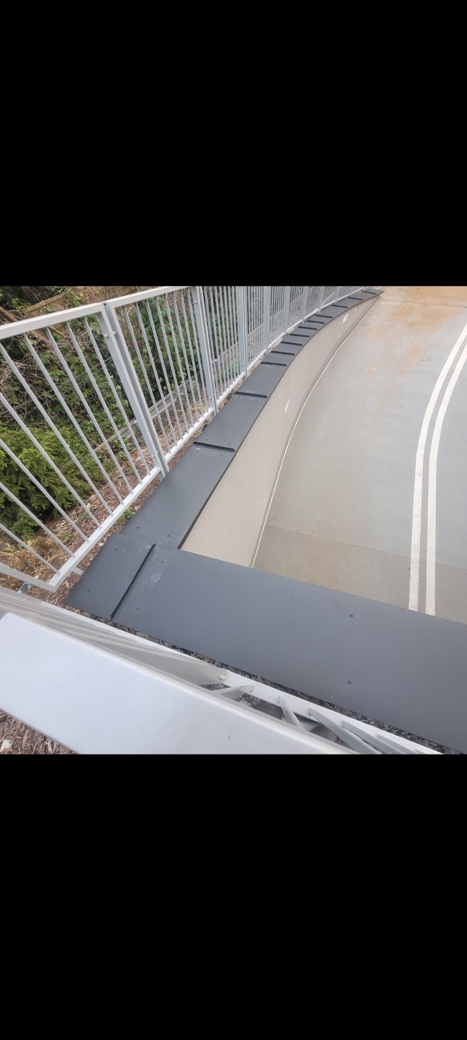 Szare panele na dachu z białymi barierkami, widok z góry.