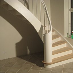 INN MARKET SP. Z O.O. - Klatka schodowa z białymi, kręconymi schodami z drewnianymi stopniami, widok z dołu, na parapecie okiennym butelki z płynami.