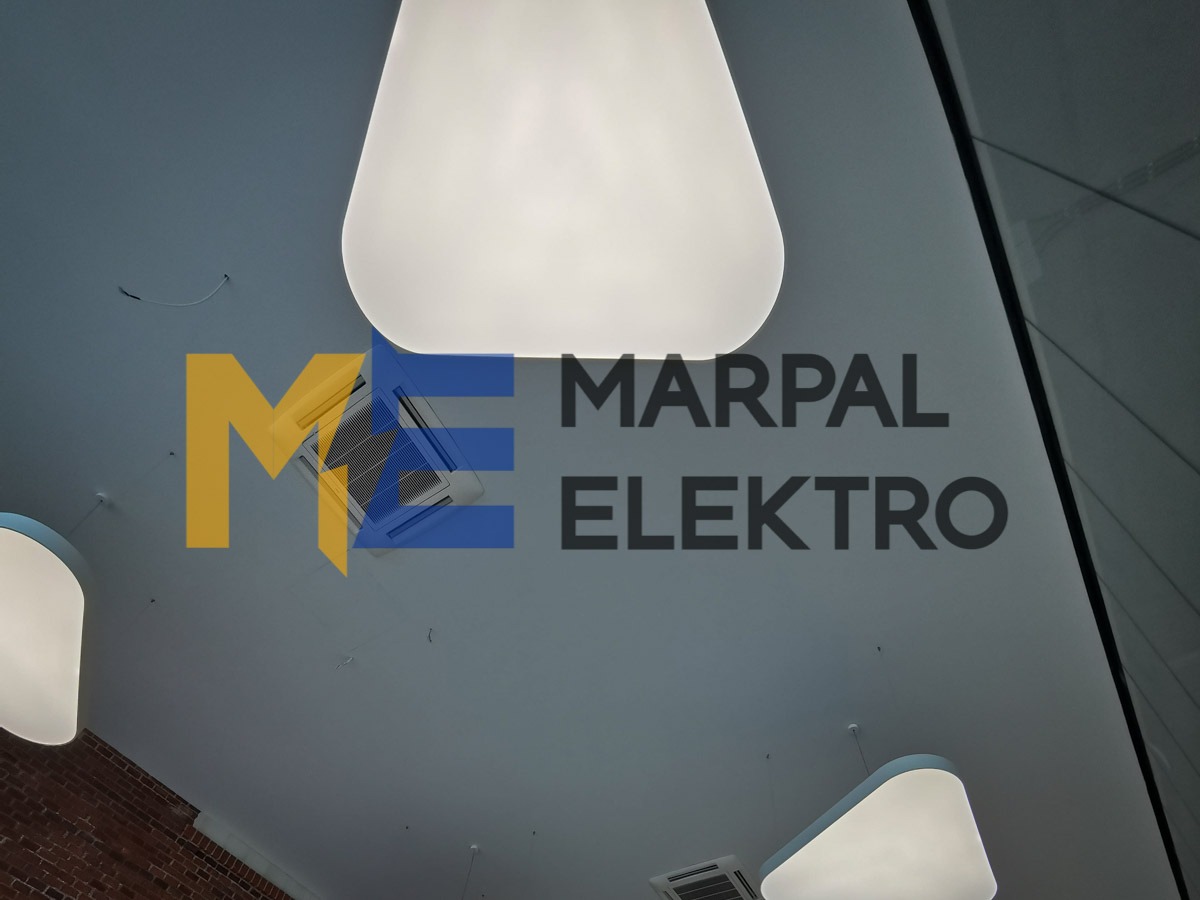 Widok z dołu na sufit z nowoczesnym oświetleniem w kształcie zaokrąglonych kwadratów, widoczny system klimatyzacji i logo firmy Marpal Elektro