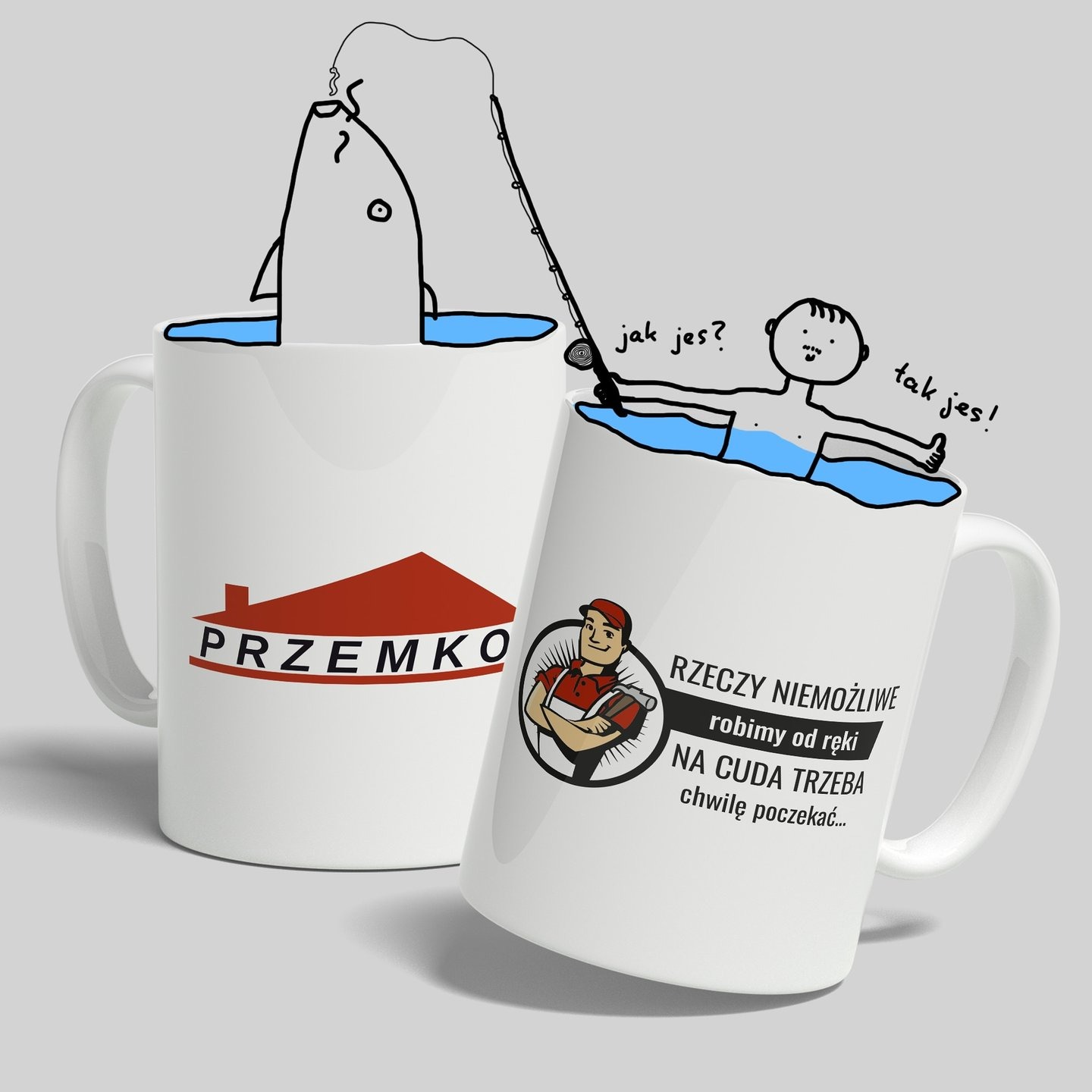 Dwa białe kubki z nadrukami: jeden z logotypem firmy 'PRZEMKO' z czerwoną ikoną domu, drugi z rysunkiem majsterkowicza i tekstem 'RZECZY NIEMOŻLIWE robimy od ręki NA CUDA TRZEBA chwilę poczekać...'...