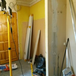 G-M-BUD - Przygotowania do prac wykończeniowych: widoczne ślady po instalacji elektrycznej wypełnione gipsem, narzędzia pracy, torba monterska, profile metalowe i worki z zaprawą gipsową w pomieszczeniu...