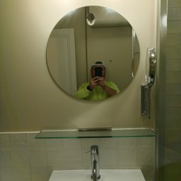 G-M-BUD - Nowoczesna umywalka z baterią, okrągłe lustro z podświetleniem i regulowane lusterko kosmetyczne w odnowionej łazience, widoczne odbicie osoby robiącej zdjęcie.