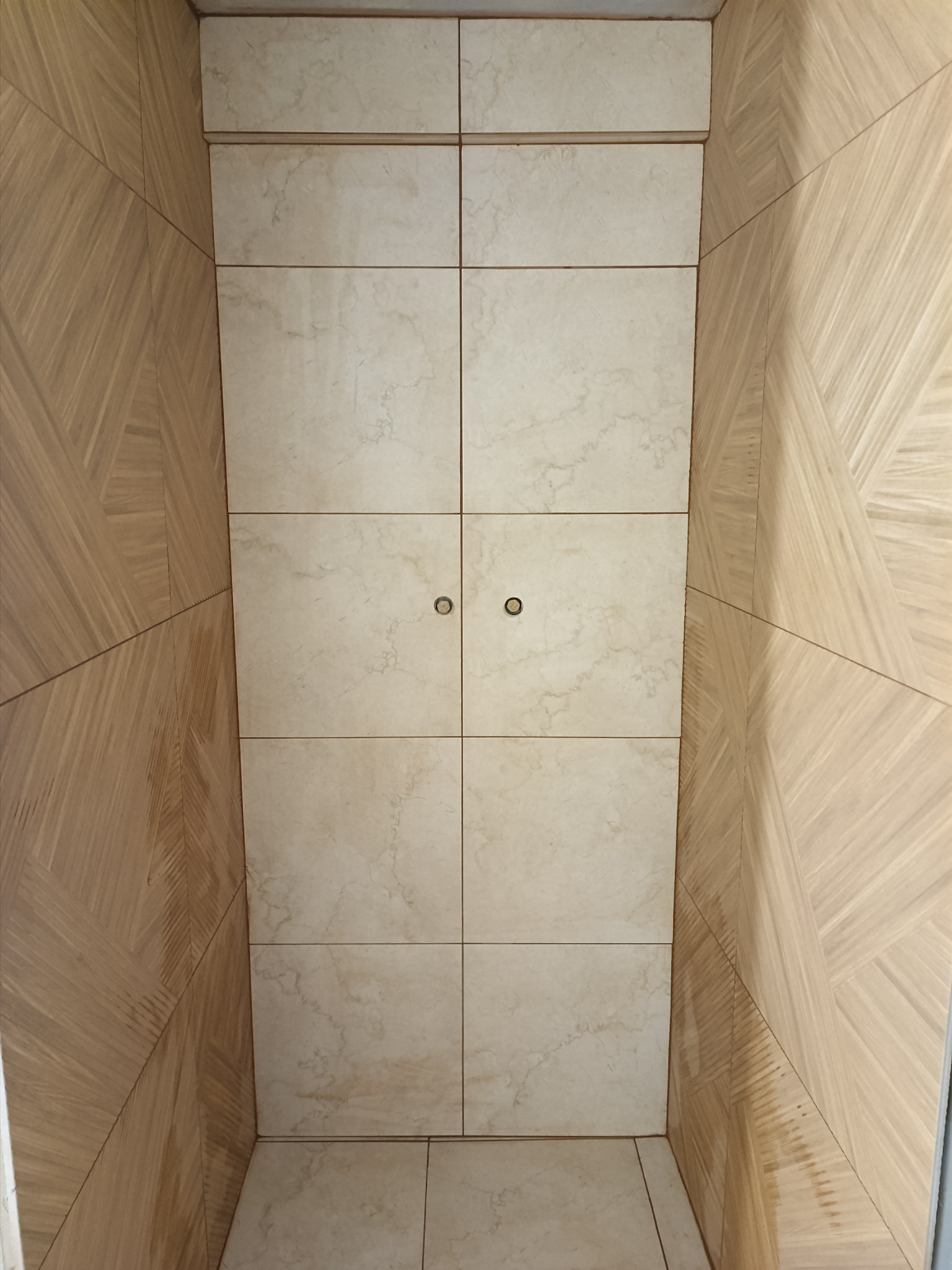 Wnętrze wykończone płytkami imitującymi marmur na ścianie frontowej oraz drewnopodobnymi panelami ułożonymi w geometryczny wzór na ścianach bocznych, widoczne dwa okrągłe uchwyty.