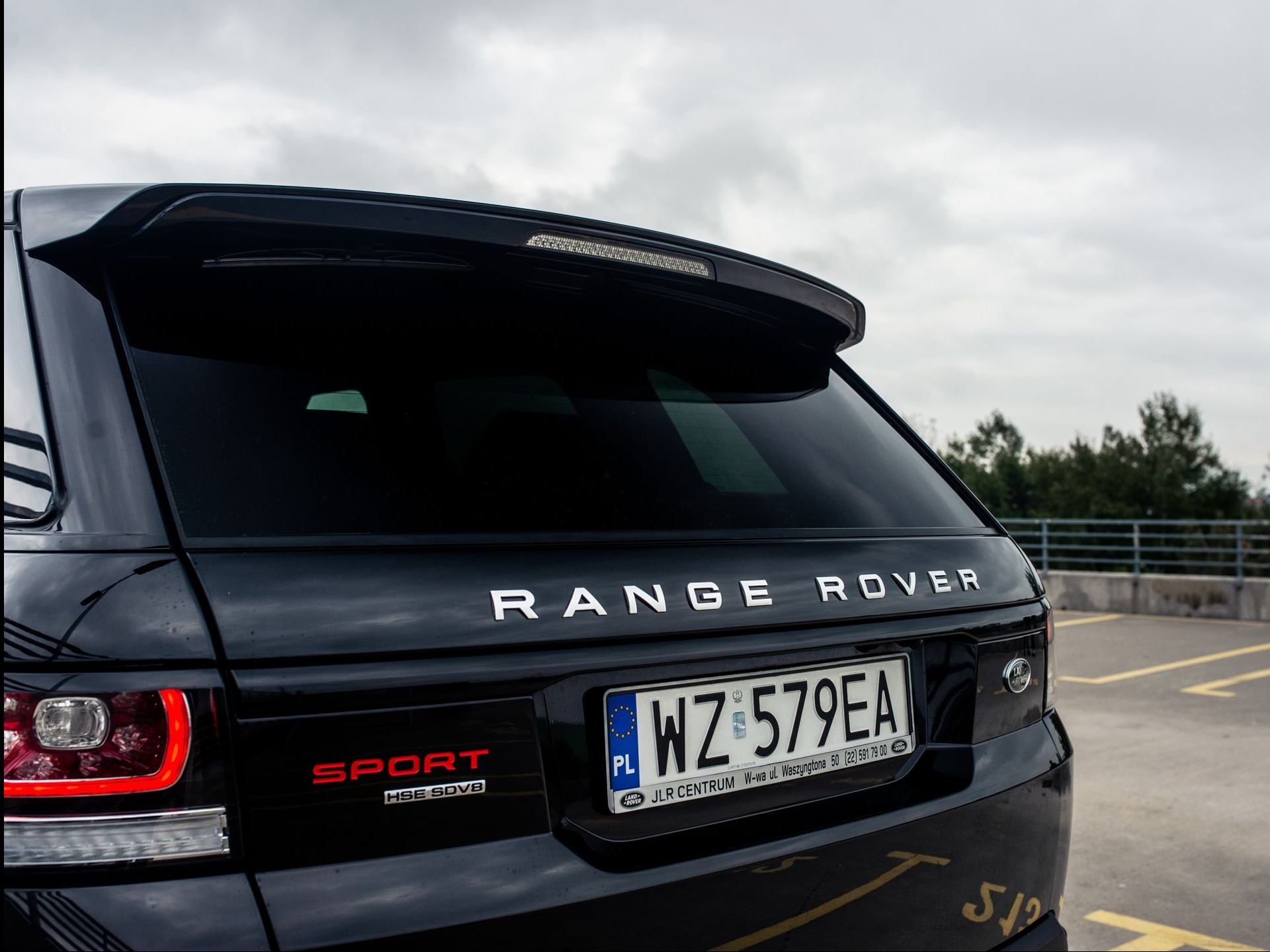 Tył czarnego Range Rover Sport z widoczną tablicą rejestracyjną WZ 579EA na parkingu, z napisem RANGE ROVER i oznaczeniem SPORT HSE SDV8.
