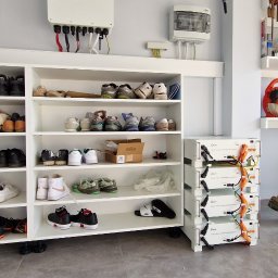 Mark-OZE sp z o. o. - Biały inwerter fotowoltaiczny i moduły akumulatorowe Daye w garażu obok regału na buty, widoczne okablowanie i skrzynka elektryczna.