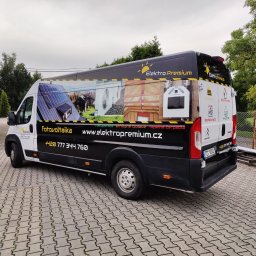 Agencja Promocyjno-Reklamowa SPOT s.c. Piotr Czerwiński, Wojciech Krawczyk - Oklejony samochód dostawczy firmy Elektro Premium z grafikami przedstawiającymi fotowoltaikę, rekuperację, izolacje natryskowe i pompy ciepła, zaparkowany na brukowanym podjeździe