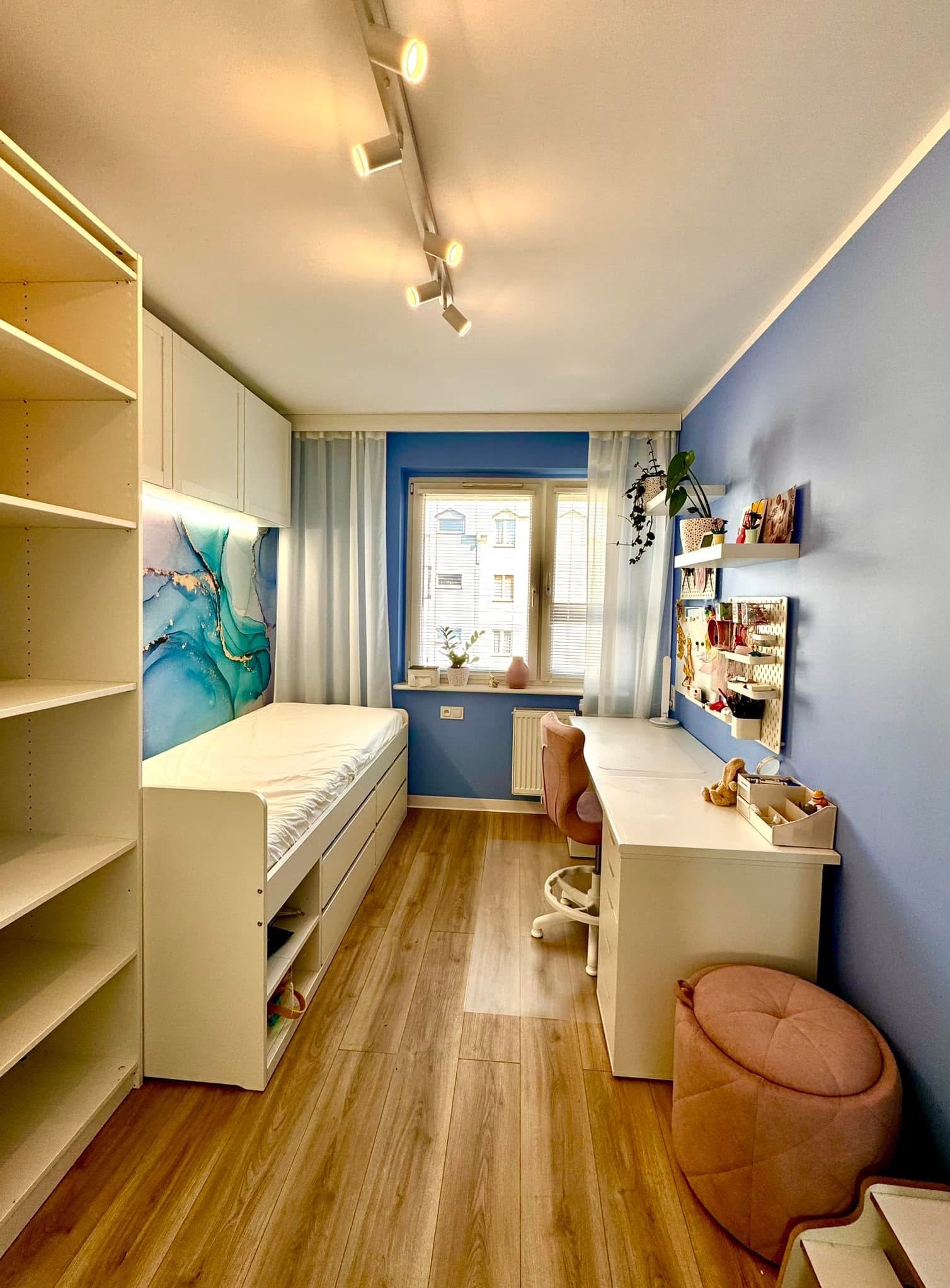 Pokój młodzieżowy w odcieniach błękitu i bieli, z łóżkiem z szufladami, biurkiem z organizerem i regałem na książki, oświetlony punktowymi lampami sufitowymi.