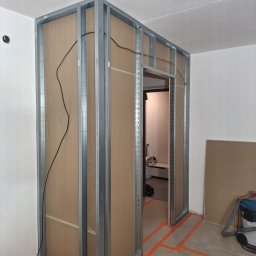 Ivan Katrych - Konstrukcja ścianki działowej z profili stalowych i płyt karton-gips, widoczne przewody elektryczne, przygotowanie do dalszych prac wykończeniowych.