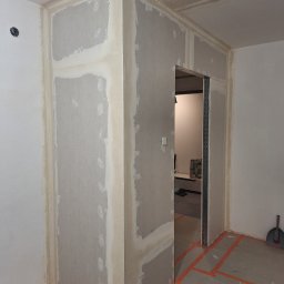 Ivan Katrych - Wnętrze w trakcie prac wykończeniowych: ściany z płyt karton-gips, widoczne łączenia i szpachlowanie, przygotowane do dalszych prac. Na podłodze taśmy zabezpieczające.