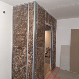 Ivan Katrych - Ściana z izolacją z wełny mineralnej w metalowym stelażu, widok na otwór drzwiowy. Przygotowanie do montażu płyty gipsowo-kartonowej wewnątrz pomieszczenia.