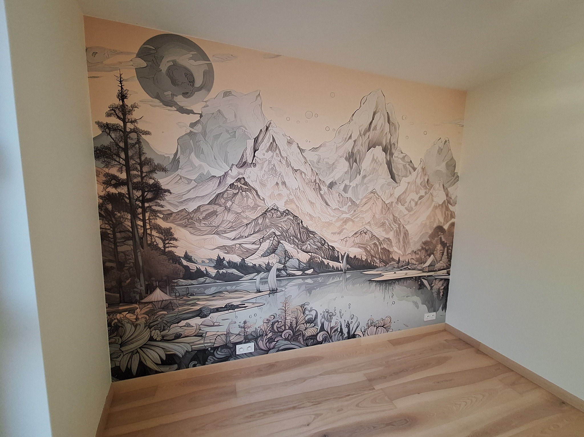 Pokój z fototapetą przedstawiającą górski krajobraz z jeziorem i żaglówkami, utrzymaną w stonowanej kolorystyce. Widoczne gniazdka elektryczne przy podłodze i panele podłogowe.