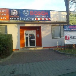 Pw Reda - Fasada budynku z pomarańczowym wejściem, szyldami reklamowymi Bosch i Sebnar oraz tablicą Partner Agencja Reklamowa