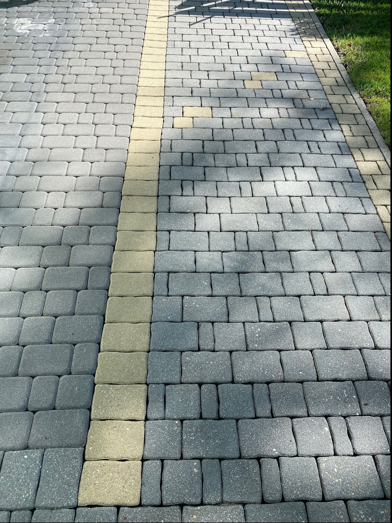 Szara kostka brukowa z żółtym pasem po prawej stronie, ułożona na zewnątrz, widok z góry.