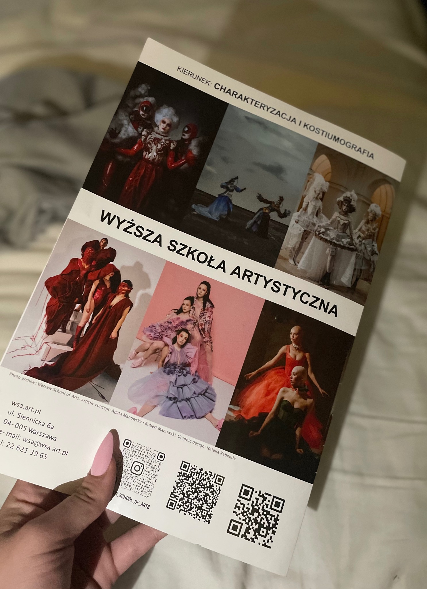 Katalog Wyższej Szkoły Artystycznej prezentujący zdjęcia kostiumów i charakteryzacji, trzymany w dłoni.