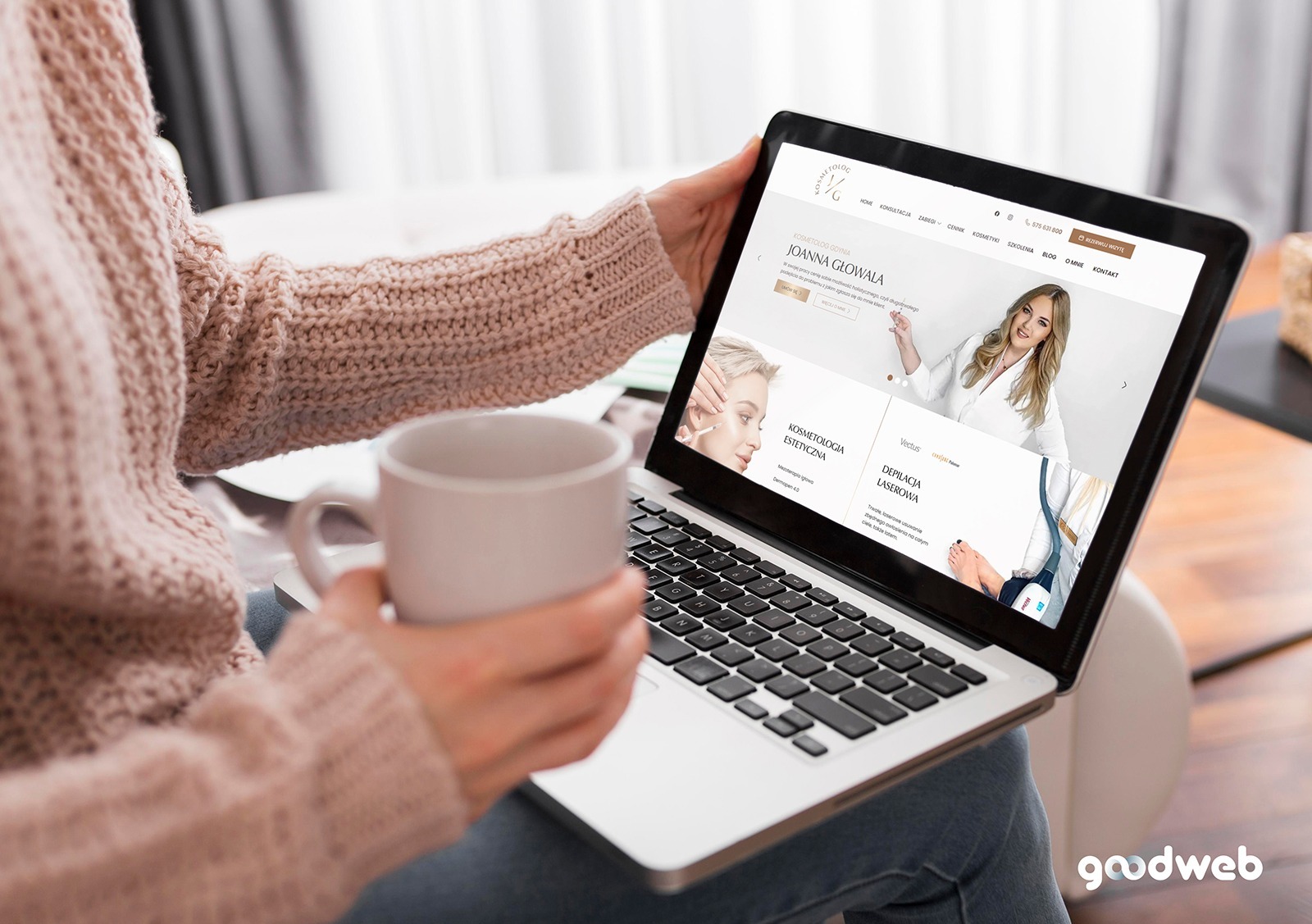 Kobieta w swetrze trzyma kubek z napojem, przeglądając na laptopie stronę internetową kosmetyczki Joanny Głowala z ofertą kosmetologii estetycznej i depilacji laserowej.