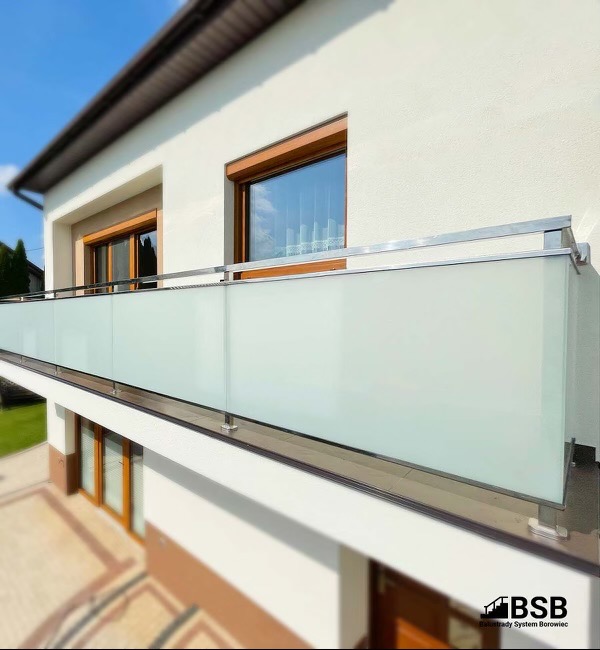 Balkon z nowoczesną balustradą ze szkła matowego i stali nierdzewnej, widok z dołu, z logo producenta w prawym dolnym rogu.