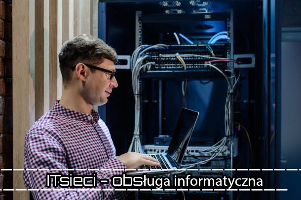 Inżynier w okularach, pracujący na laptopie przed szafą serwerową w Warszawie, z widocznymi kablami i urządzeniami sieciowymi.