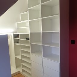 Omeblowani Mariusz Jastrzębski - Biała zabudowa szafy wnękowej na poddaszu ze skosami, z półkami i szufladami, oświetlenie punktowe na suficie.