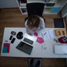 Kobieta siedzi przy biurku z laptopem, notatnikiem i kalkulatorem, analizując dane w biurze z widokiem z góry.