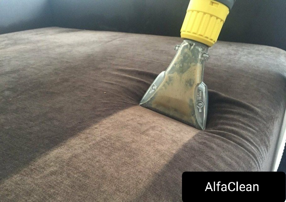 Dysza odkurzacza piorącego w trakcie czyszczenia brązowej, welurowej kanapy, widoczne ślady wilgoci po czyszczeniu.