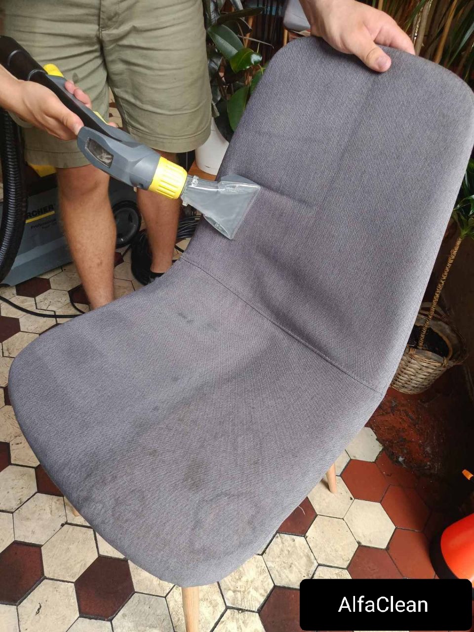 Szara tapicerowana krzesło czyszczone parowo z użyciem odkurzacza Karcher, widoczne plamy na siedzisku przed czyszczeniem.