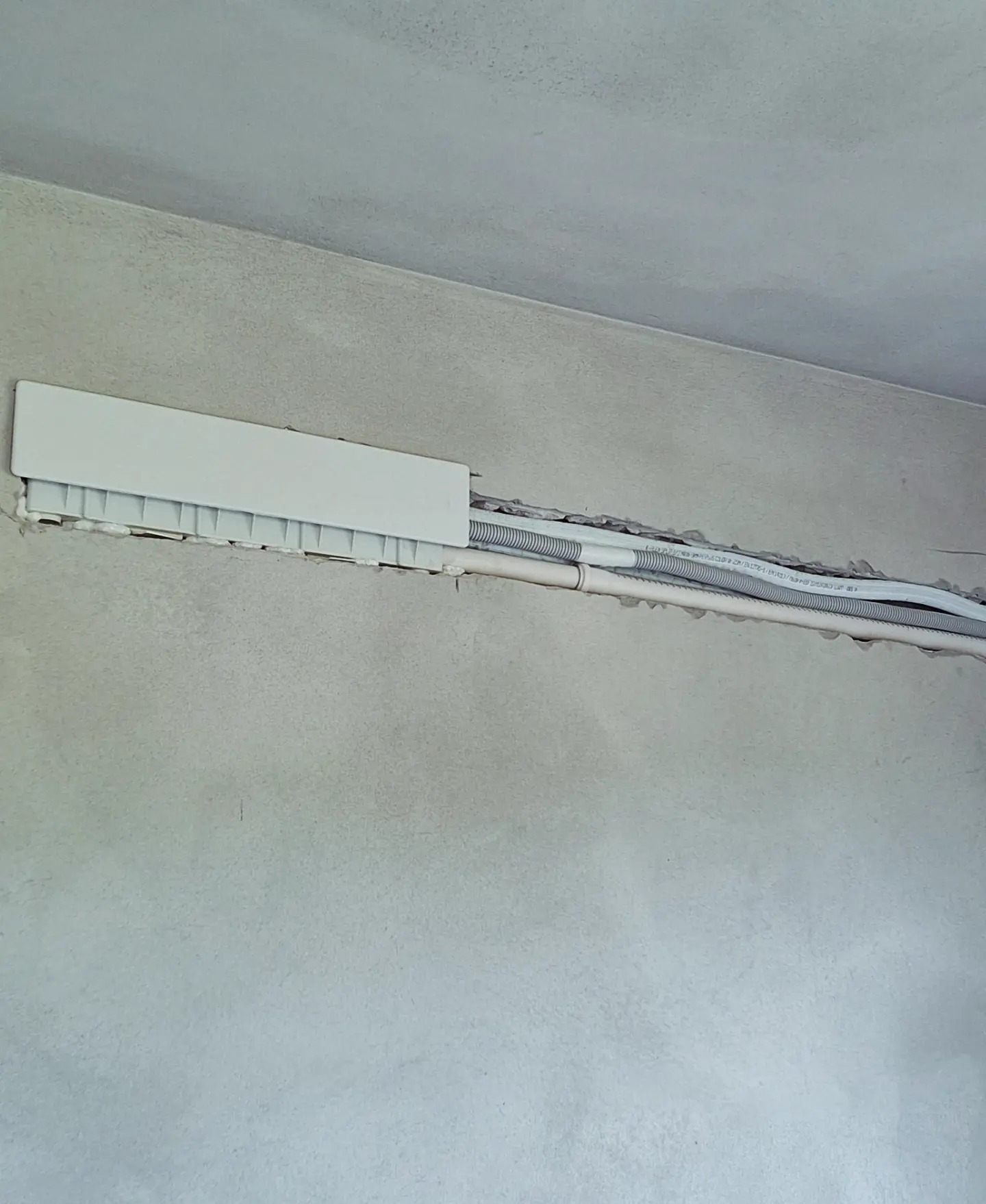 Instalacja rur w ścianie pod osłoną, widoczne rury karbowane i gładkie, ściana w stanie surowym.