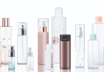 Różnorodne, puste butelki i pojemniki z tworzywa sztucznego, niektóre z atomizerami, w odcieniach bieli, różu i brązu, ustawione na białym tle. Na niektórych butelkach widoczne delikatne motywy...