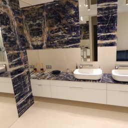 CREATIVO - Elegancka, nowoczesna łazienka we Wrocławiu z blatem z ciemnego kamienia o unikalnym wzorze, białymi szafkami pod umywalkami i dużymi lustrami.