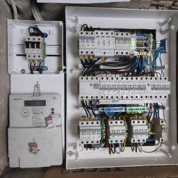VOLT GREMIUM KAROL MICHAŁEK - Rozdzielnia elektryczna z licznikiem w Trzebnicy, widoczne zabezpieczenia nadprądowe i różnicowoprądowe, kable w kolorach niebieskim, żółto-zielonym i czarnym.