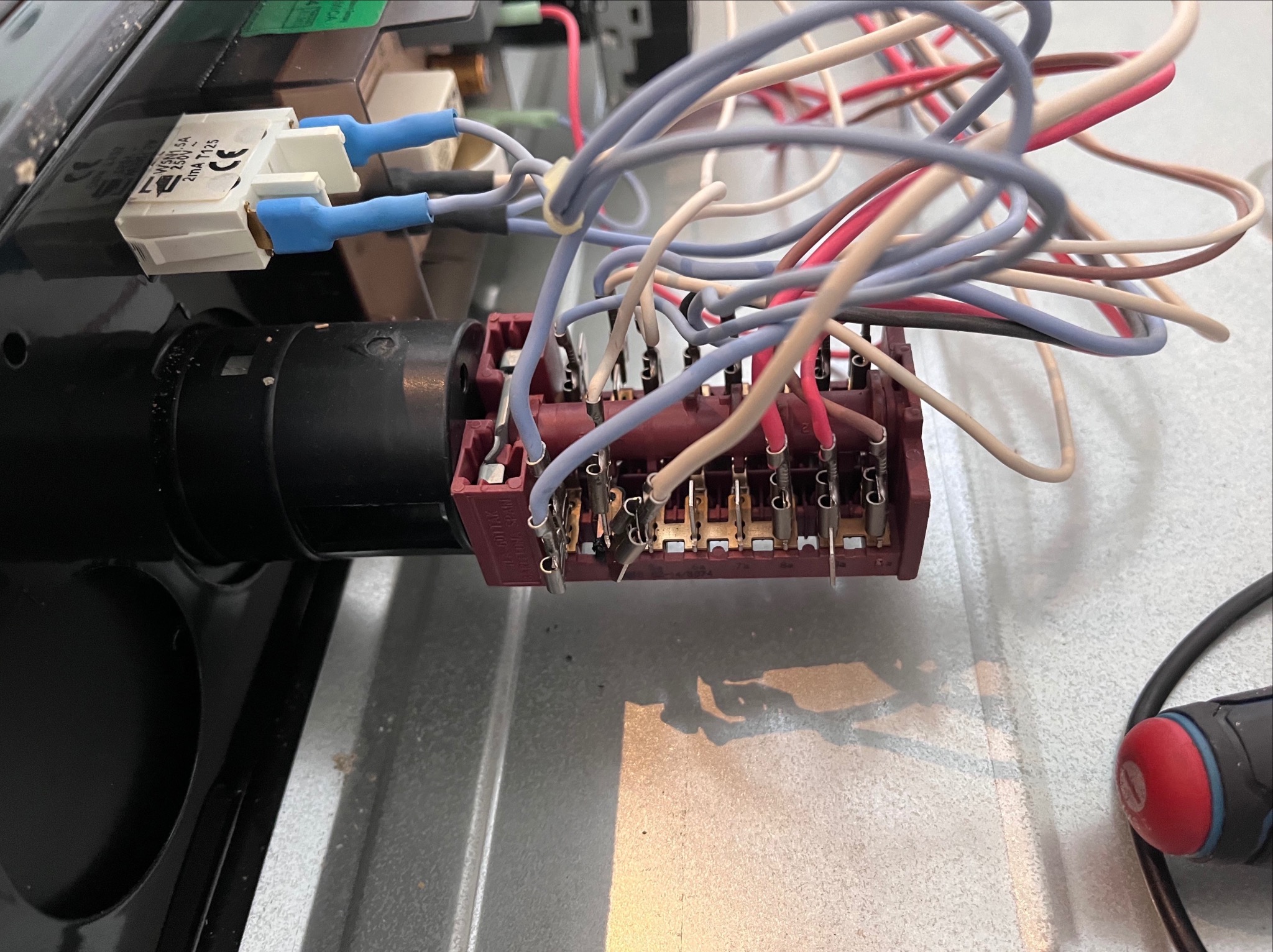 Wnętrze piekarnika z widocznym przełącznikiem, okablowaniem i elementami elektroniki w trakcie naprawy lub diagnostyki.