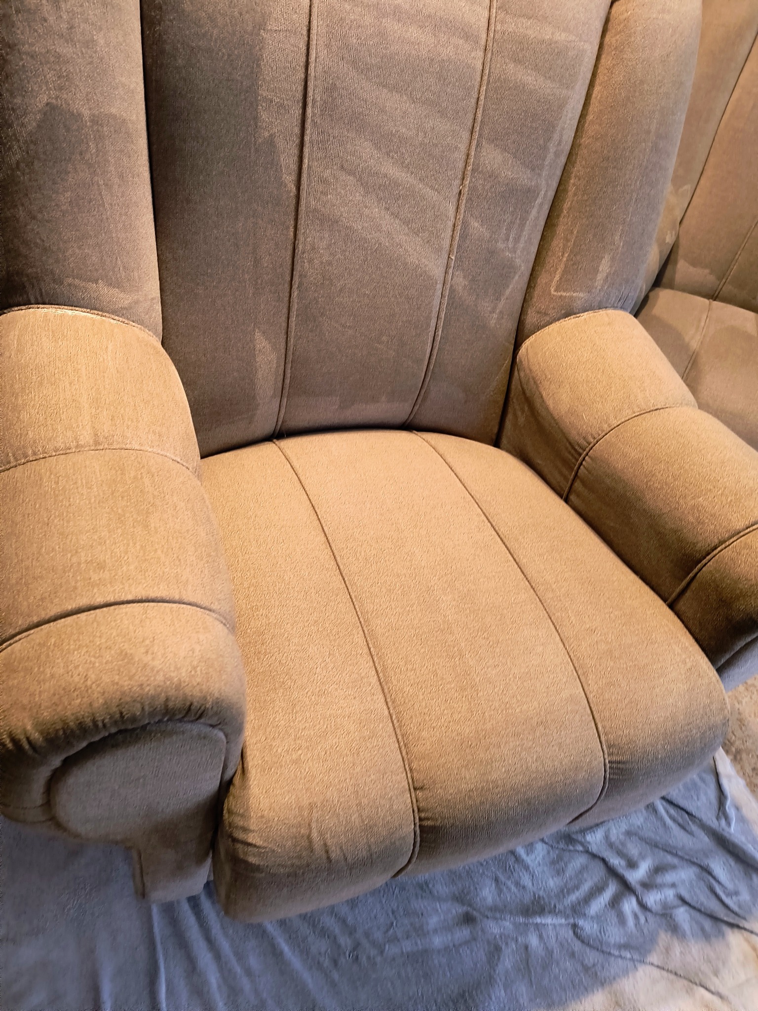 Beżowy fotel z widocznymi śladami po czyszczeniu, z wyraźnym kontrastem między wyczyszczonymi a nieoczyszczonymi obszarami tapicerki.