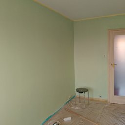 Krzysztof Marcińczyk - Pokój w trakcie malowania na jasnozielony kolor, zabezpieczony folią malarską, widoczna puszka z farbą Dulux, wałek i taboret.