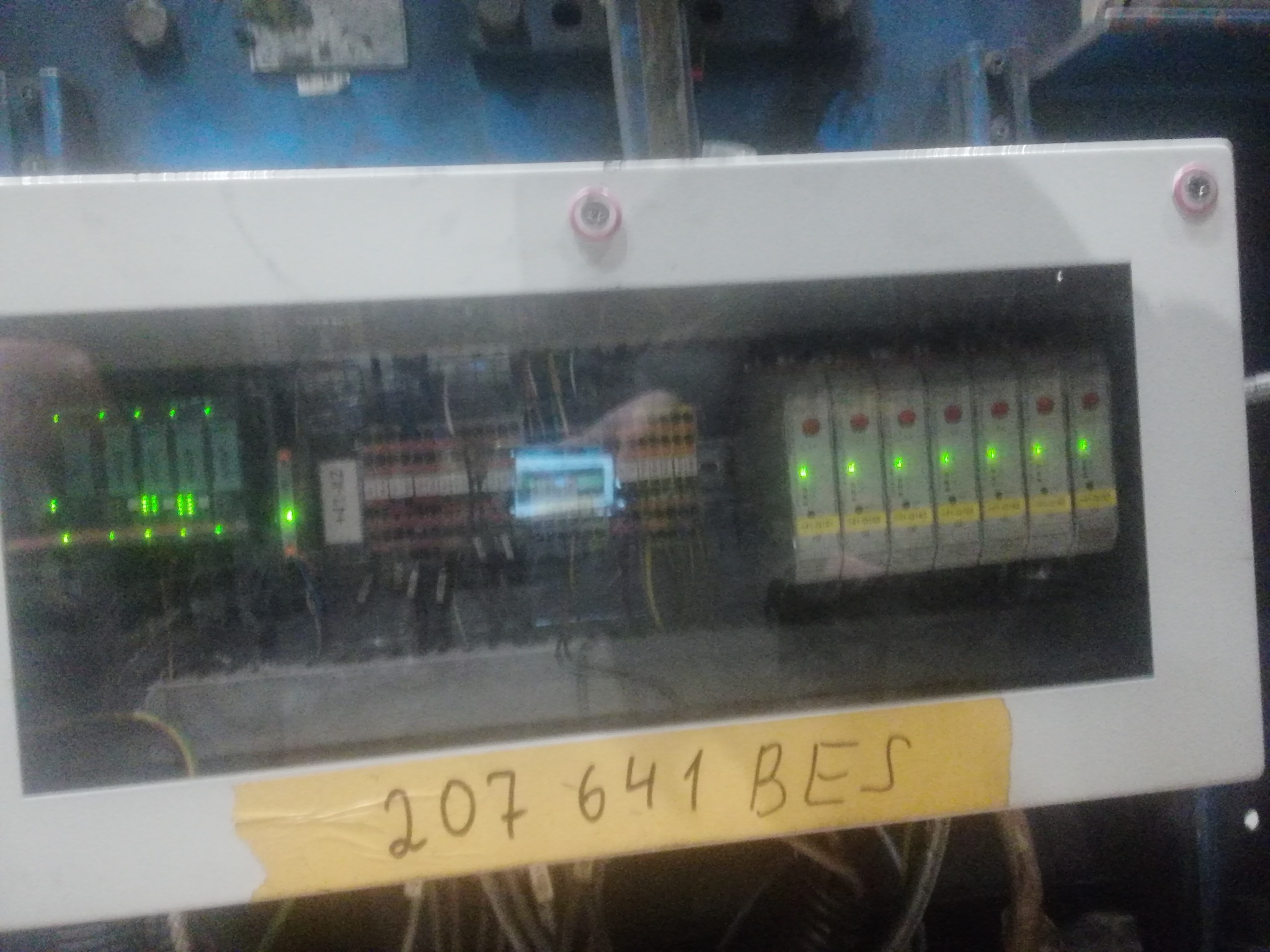 Tablica rozdzielcza w białej obudowie z widocznymi przewodami i elementami elektronicznymi, z naklejoną etykietą z numerem '207 641 BES', oświetlona zielonymi diodami LED.