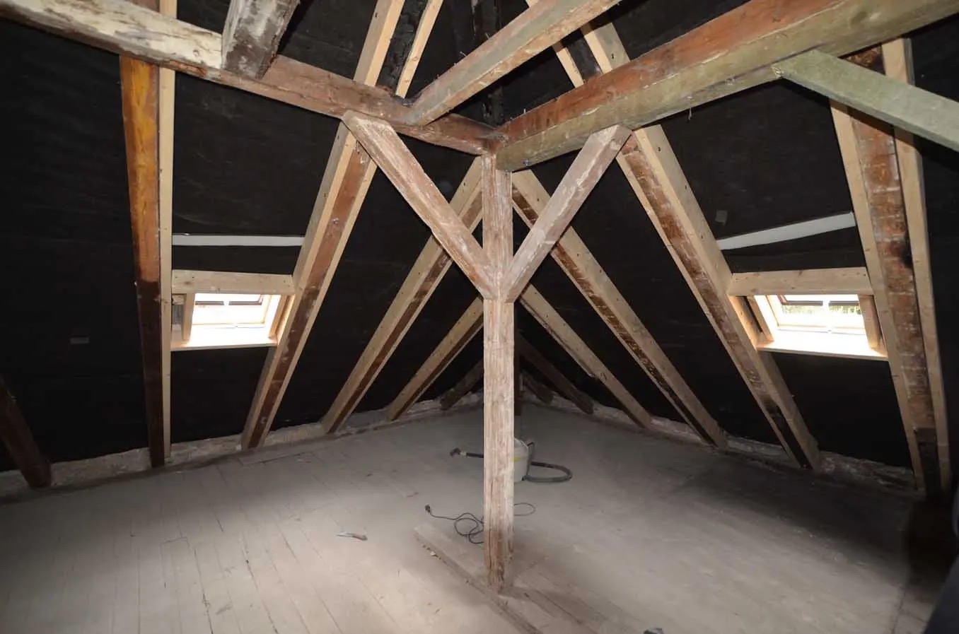 Poddasze z widoczną konstrukcją drewnianą dachu, czarną membraną oraz oknami dachowymi, przygotowane do dalszych prac wykończeniowych.