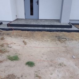 Tomasz Grzeszczak - Schody wejściowe do domu z kostki brukowej, widoczny kabel elektryczny i teren przed domem w trakcie przygotowania.