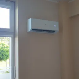 Biały klimatyzator marki Haier zamontowany na beżowej ścianie w biurze, ustawiony na temperaturę 26 stopni Celsjusza, widoczne okno i lampa sufitowa.