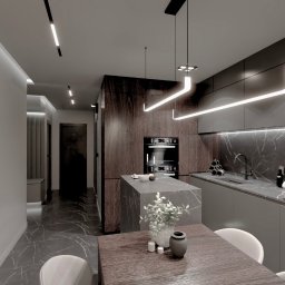 Design Atelier - Nowoczesna kuchnia z wyspą i marmurowym blatem, oświetlona ledami. Minimalistyczny design z ciemnymi frontami i drewnianymi akcentami. Na pierwszym planie stół z dekoracją.