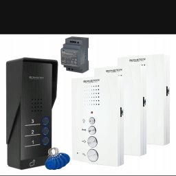 Elbaza - Zestaw wideodomofonowy Bernstein z panelem zewnętrznym w kolorze czarnym, trzema unifonami w kolorze białym i zasilaczem impulsowym, prezentowany na białym tle.