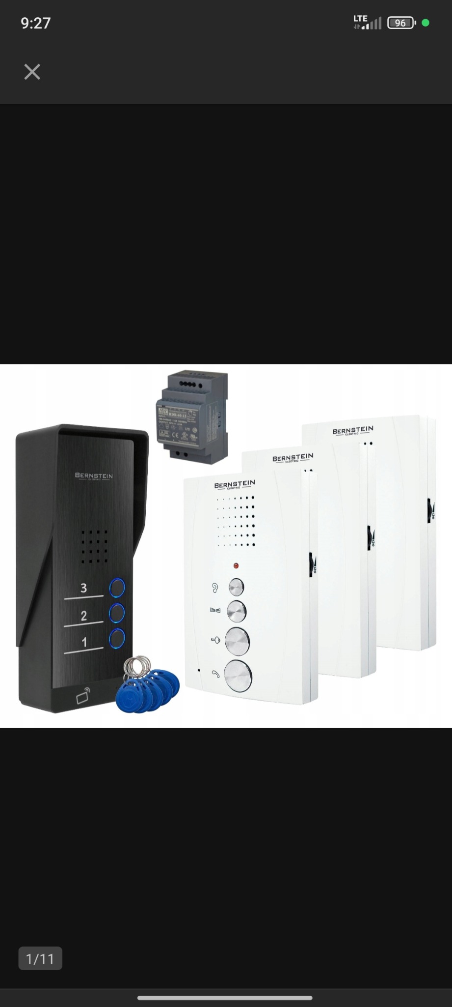 Zestaw wideodomofonowy Bernstein z panelem zewnętrznym w kolorze czarnym, trzema unifonami w kolorze białym i zasilaczem impulsowym, prezentowany na białym tle.