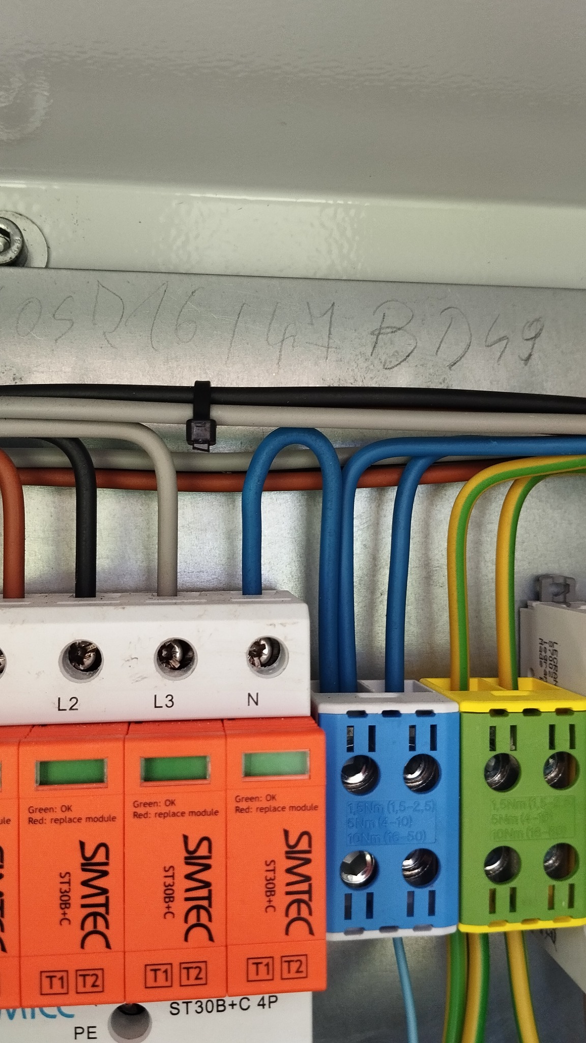 Zbliżenie na podłączone przewody w skrzynce elektrycznej, widoczne kolorowe zabezpieczenia SIMTEC z diodami sygnalizacyjnymi stanu.