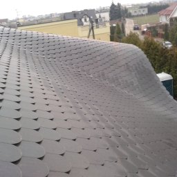 Roof Top - Pogotowie Dekarskie - Dach pokryty łuską bitumiczną z kominkami wentylacyjnymi, widok z góry na tle zabudowań i zieleni
