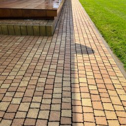 Winclear mycie okien i elewacji - Umyta kostka brukowa w odcieniach beżu i brązu, prowadząca od schodów do trawnika. Widoczne ślady wilgoci po myciu, podkreślające czystość.