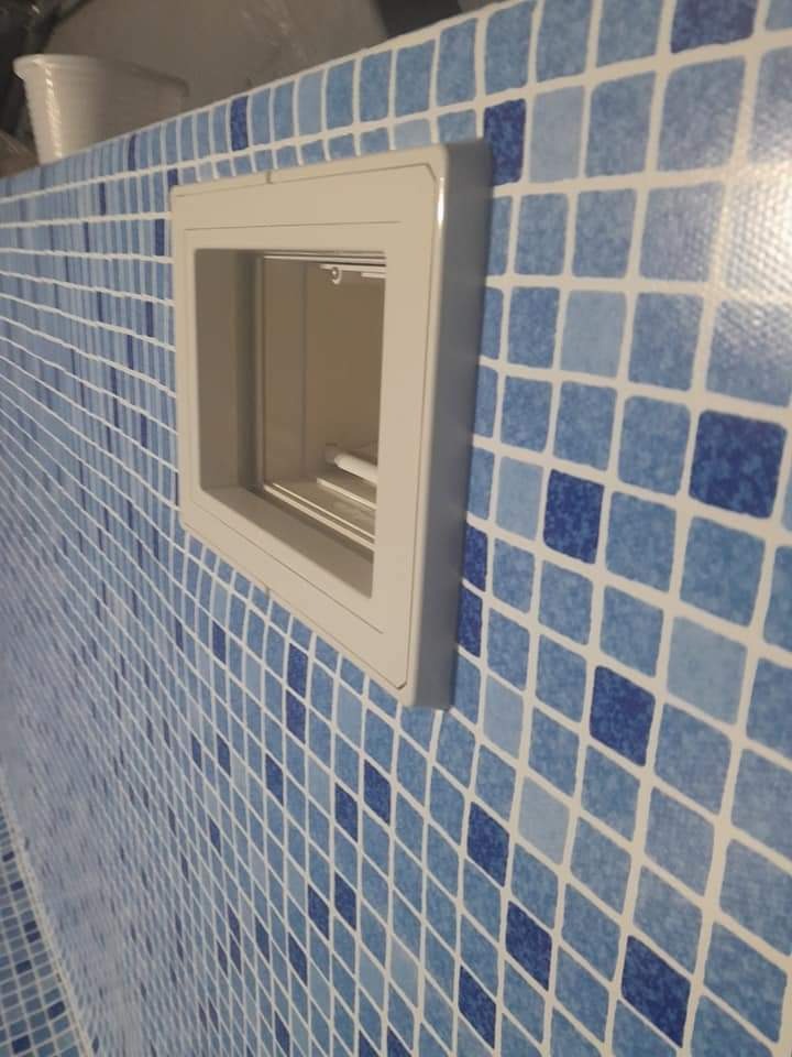 Wnęka rewizyjna w ścianie basenu wyłożonej mozaiką w odcieniach błękitu i bieli.