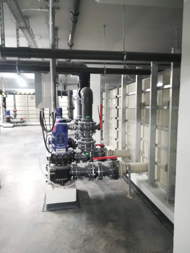 Instalacja filtracyjna z pompami SPECK w pomieszczeniu technicznym, widoczne rury, zawory i metalowe konstrukcje wsporcze.