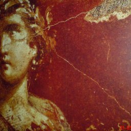 CEZARY ADAM GREZEL - Fragment muralu przedstawiający popiersie kobiety w wieńcu na tle czerwonej, popękanej ściany.